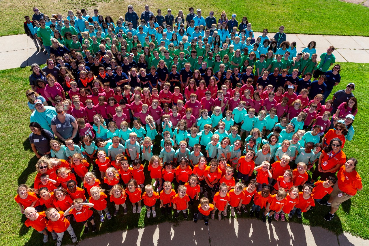 PHES students wearing different color t-shirts by grade level as seen from above in this drone image.